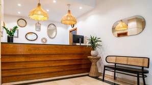 A reception area with a wooden reception desk, two hanging wicker lamps, a round mirror, and a bench. - Hôtel Casón del Tormes by HappyCulture (Madrid)