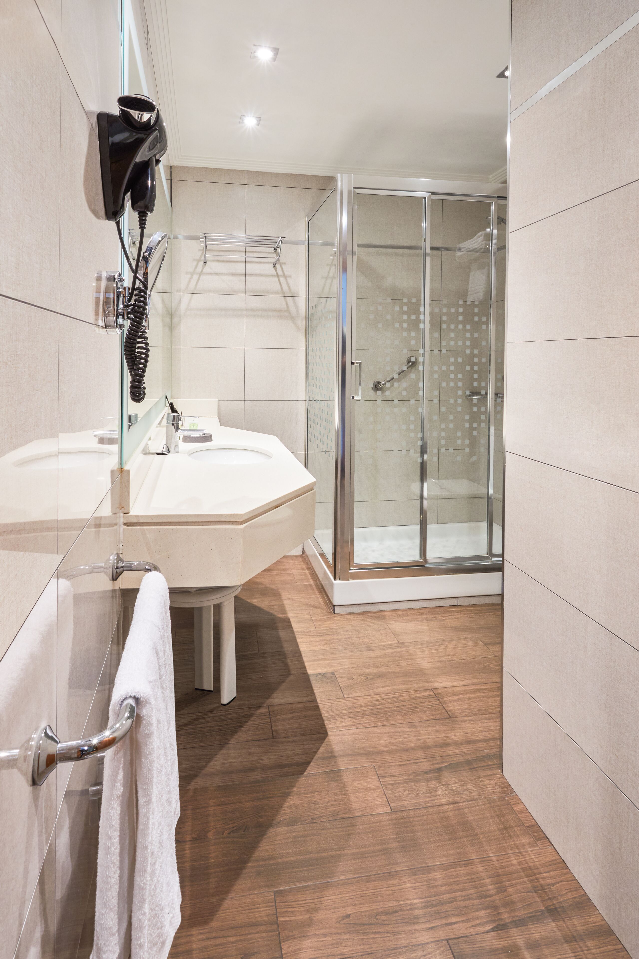 Un baño moderno con un lavamanos grande, mampara de ducha de vidrio y un perchero para toallas.