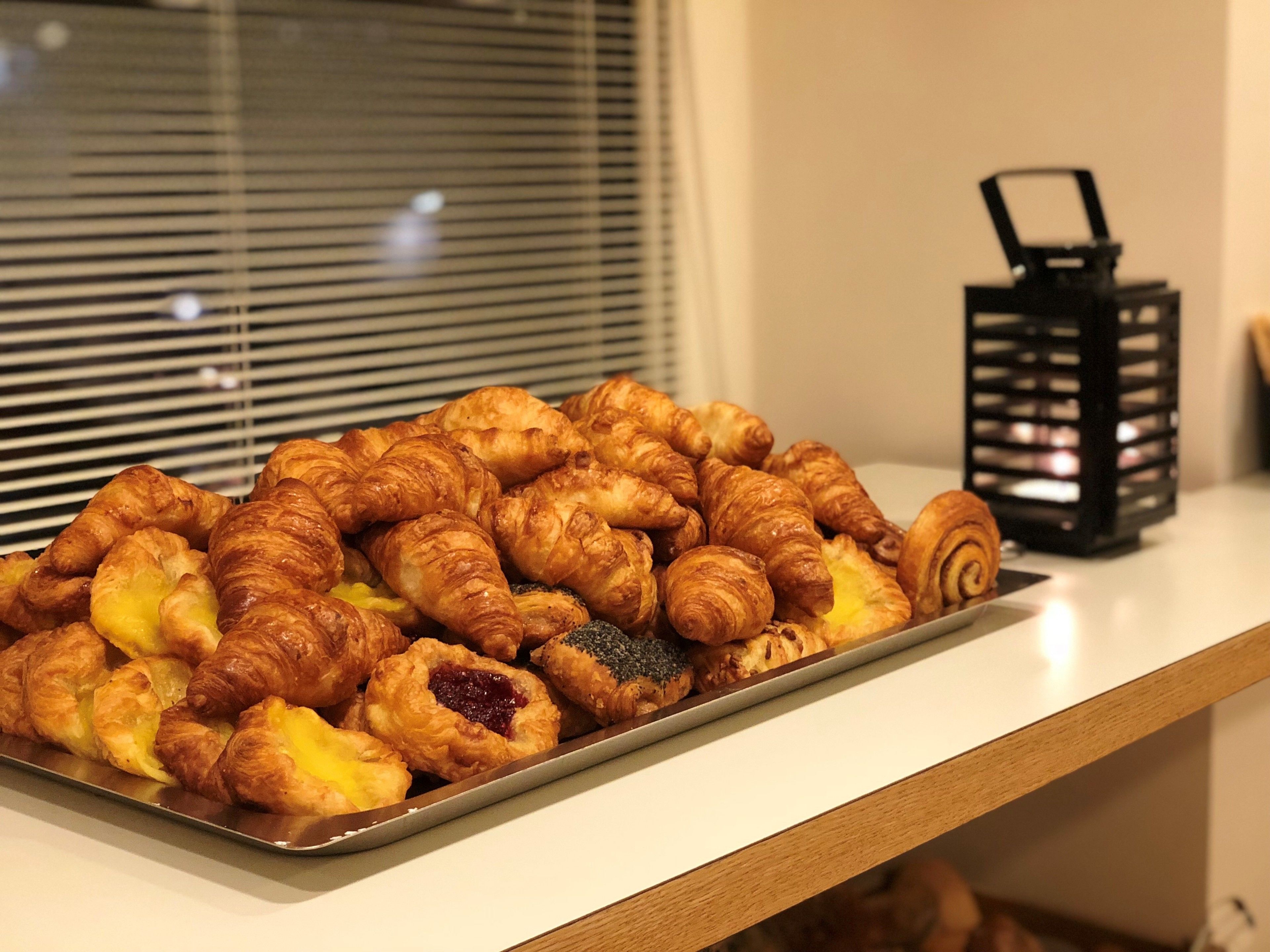 Una bandeja con diversos pasteles sobre una mesa cerca de una ventana con persianas.
