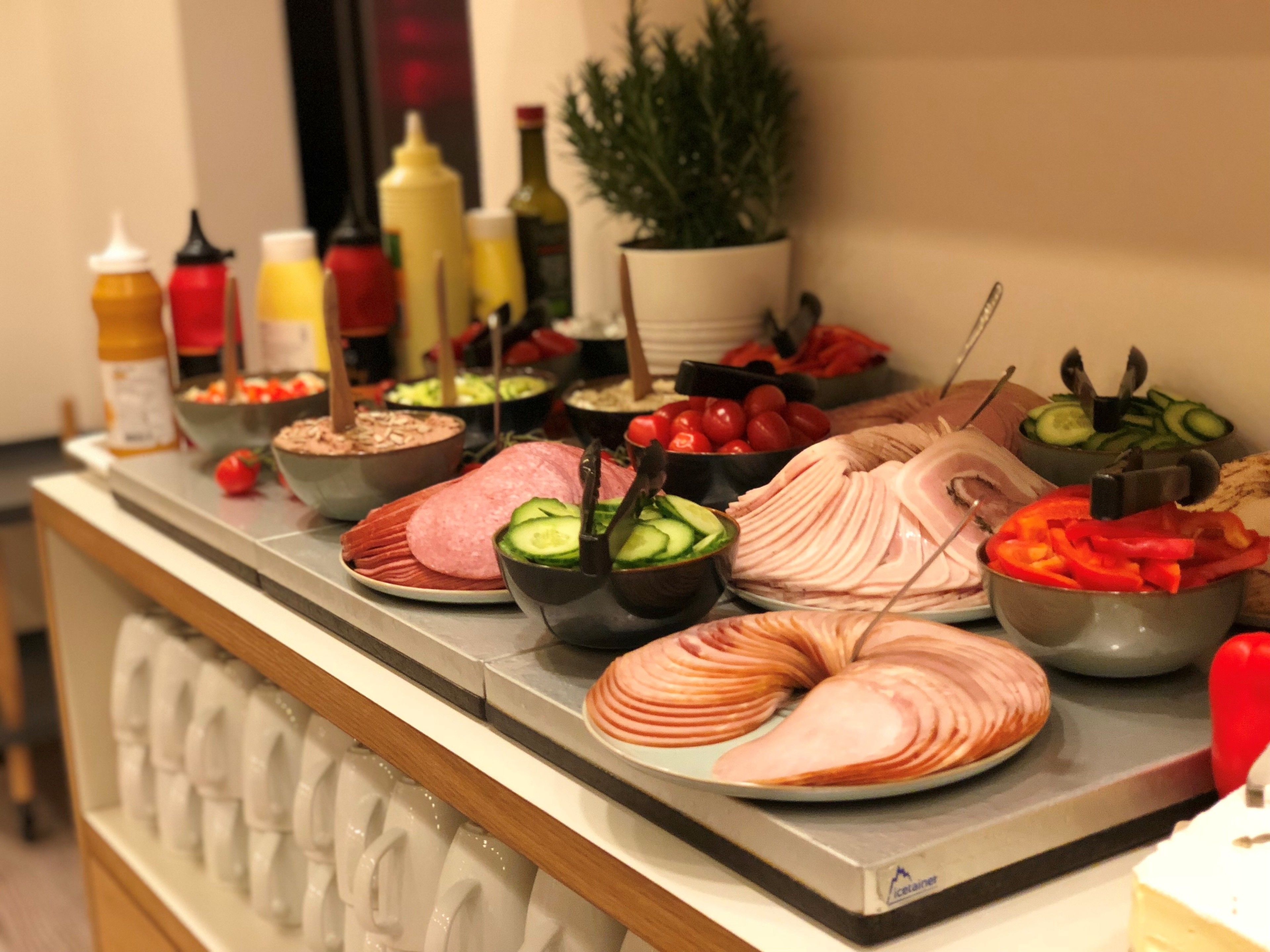 Un bufé con diversos alimentos, como embutidos, verduras y salsas.