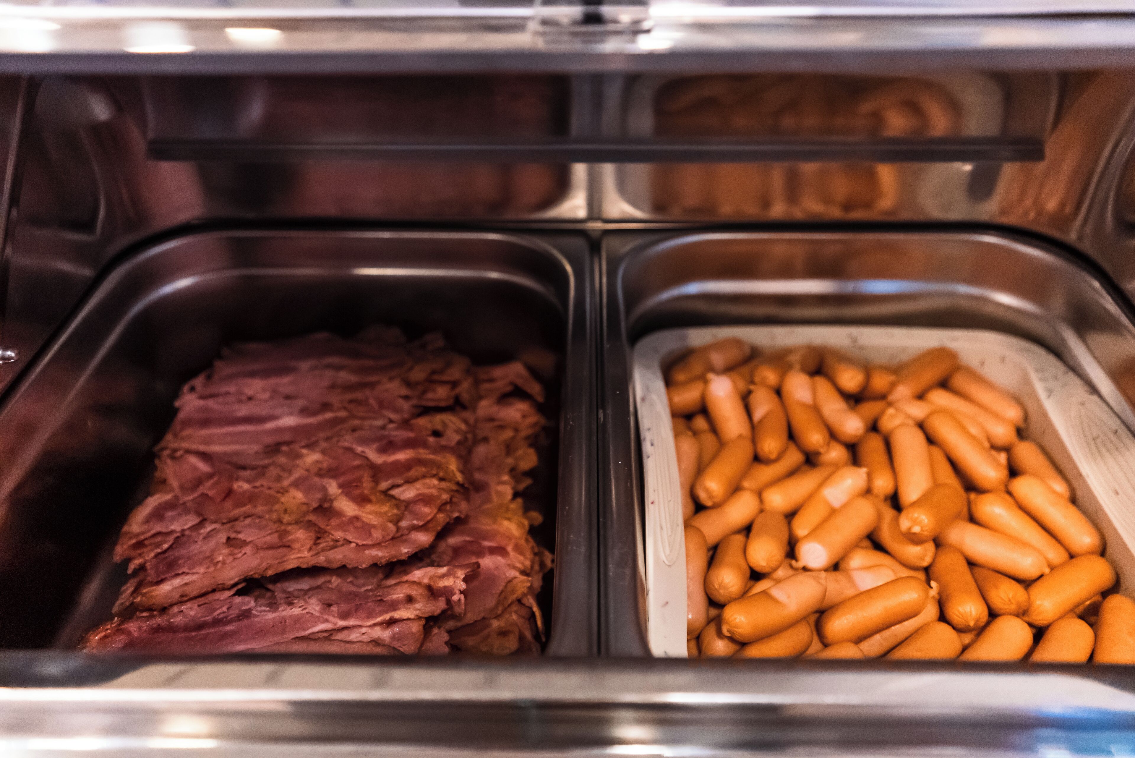 A buffet with two sections: one with sliced meat and another with sausages.