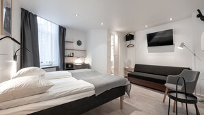 Una camera da letto moderna con un letto, un divano, una sedia, una TV e una scrivania.