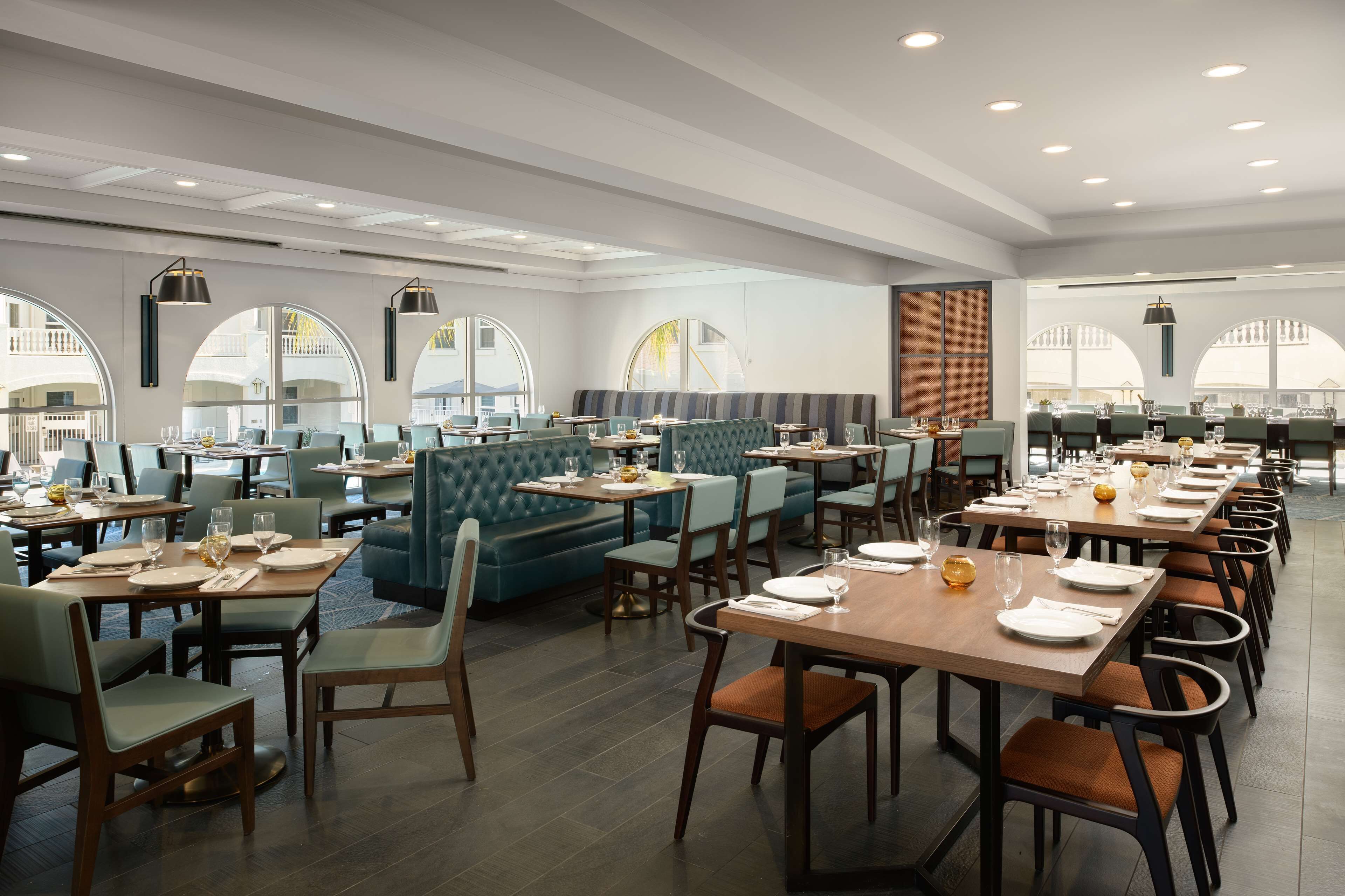 Ein geräumiges Restaurant mit mehreren Sitzbereichen, darunter gemütliche Nischen und Tische, sowie großen Fenstern mit Ausblick.