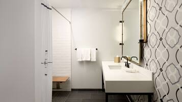 A modern bathroom with a white sink, a mirror, and a shower curtain.