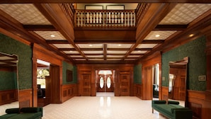 A spacious hallway with wooden paneling, green upholstered benches, and a high ceiling with a balcony. - Hayes Mansion, San Jose - Curio Collection by Hilton (San Jose)