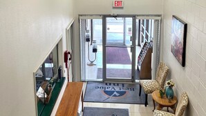 A lobby with an exit sign, a reception desk, a patterned chair, and a doormat with 'Best Value Inn' branding. - Americas Best Value Inn Laramie (Laramie)