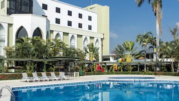Ett hotell med en swimmingpool, palmer och en lekplats för barn.