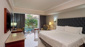 A hotel room with a bed, a desk, a chair, a TV, a lamp, and a view of the outdoors. - Holiday Inn Tuxtla Gutierrez by IHG (Tuxtla Gutierrez)