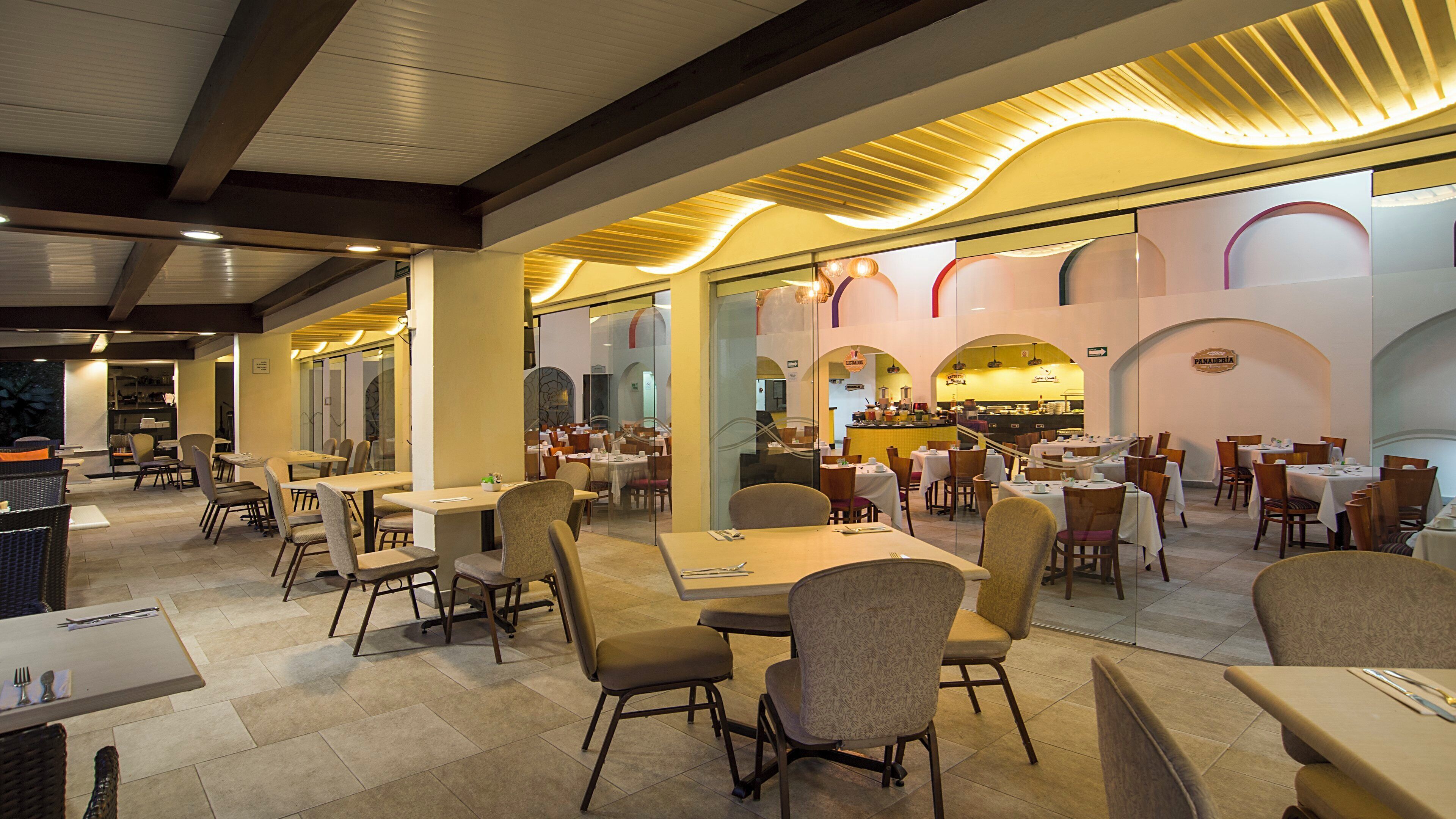 A spacious restaurant with multiple dining areas, including a bar and a seating area with tables and chairs.