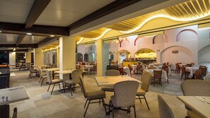 Ein geräumiges Restaurant mit mehreren Essbereichen, darunter eine Bar und eine Sitzgelegenheit mit Tischen und Stühlen.