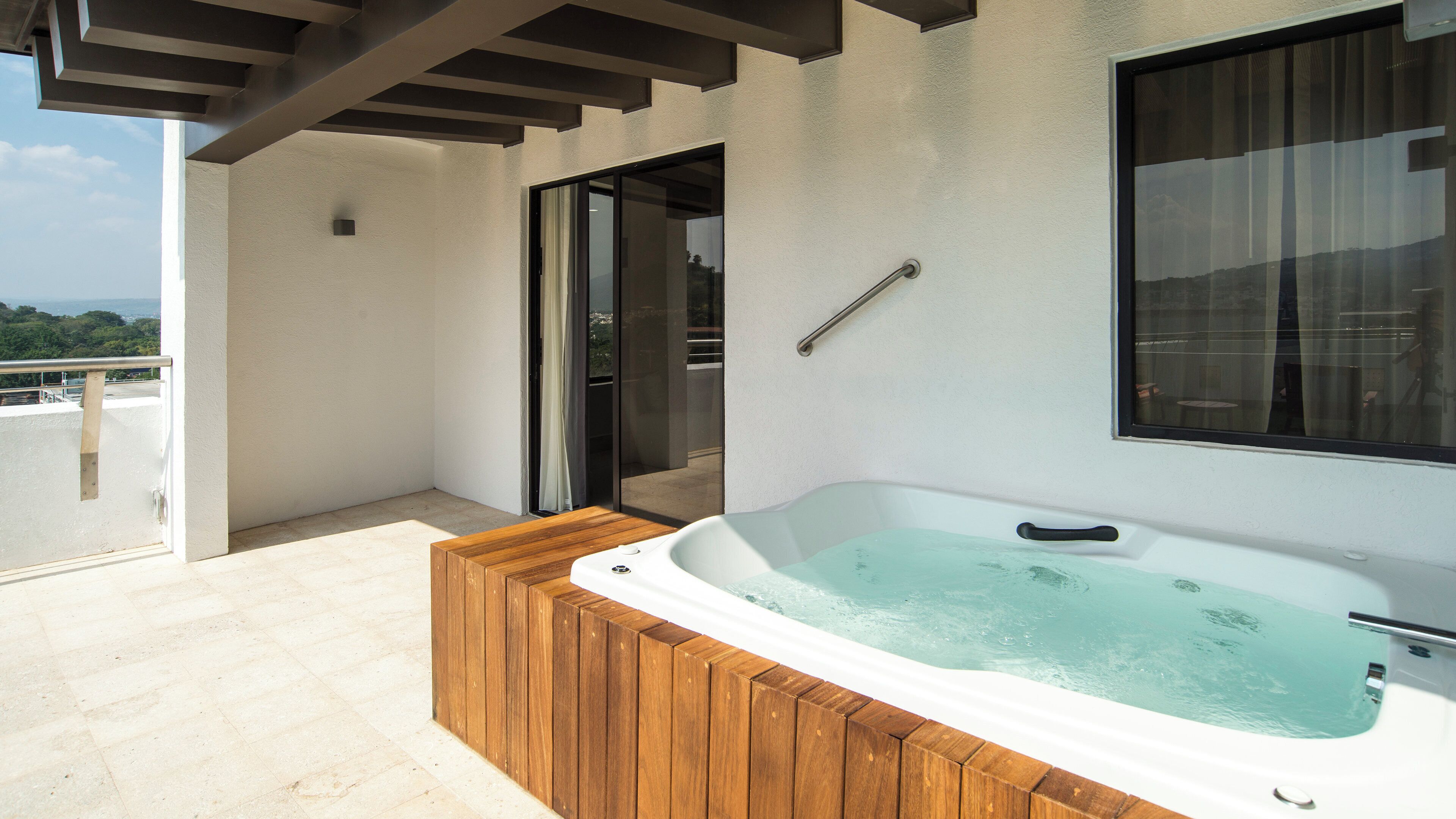 A hot tub on a balcony with a view of the outdoors.