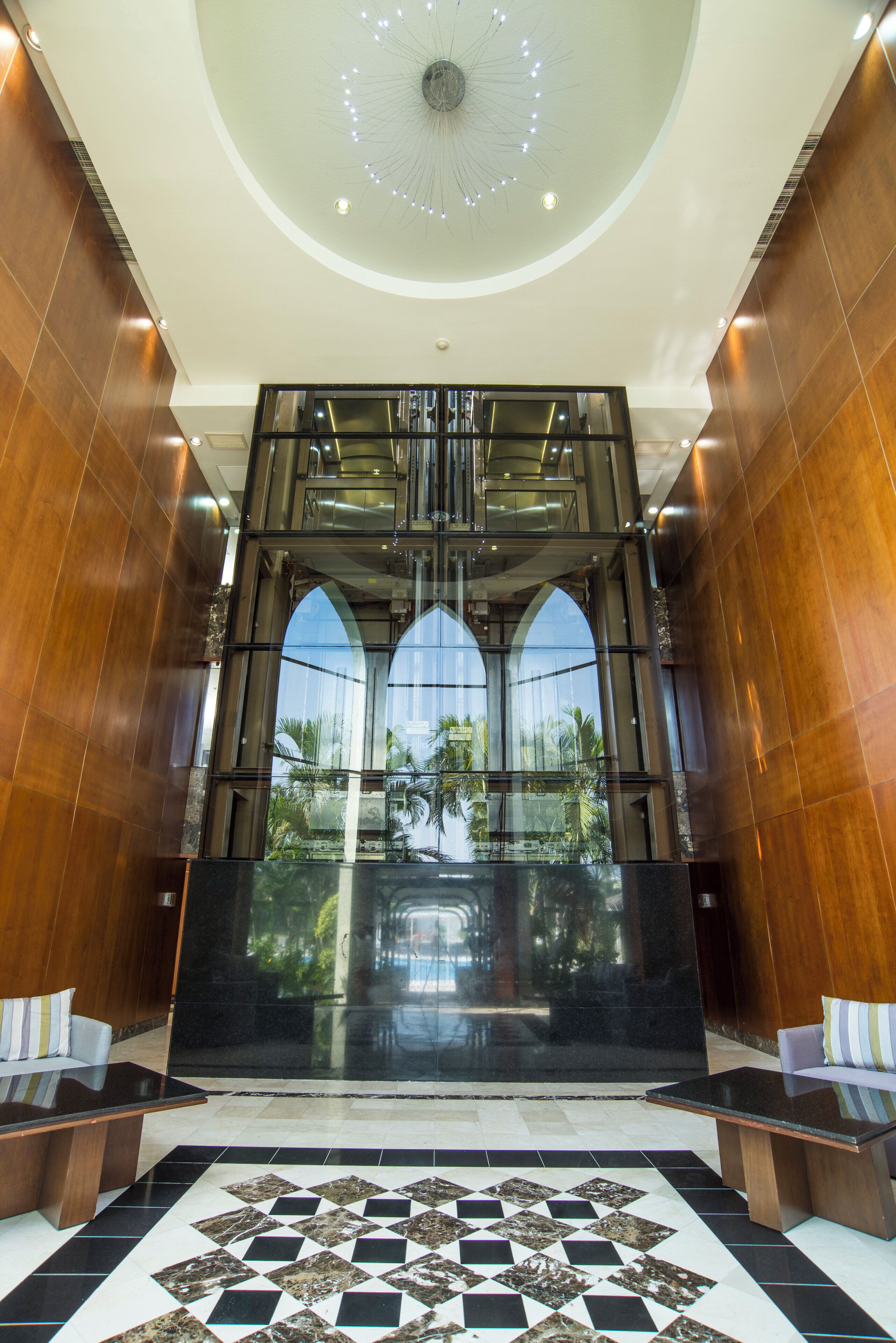 A lobby with a central elevator, a patterned floor, and wooden walls.