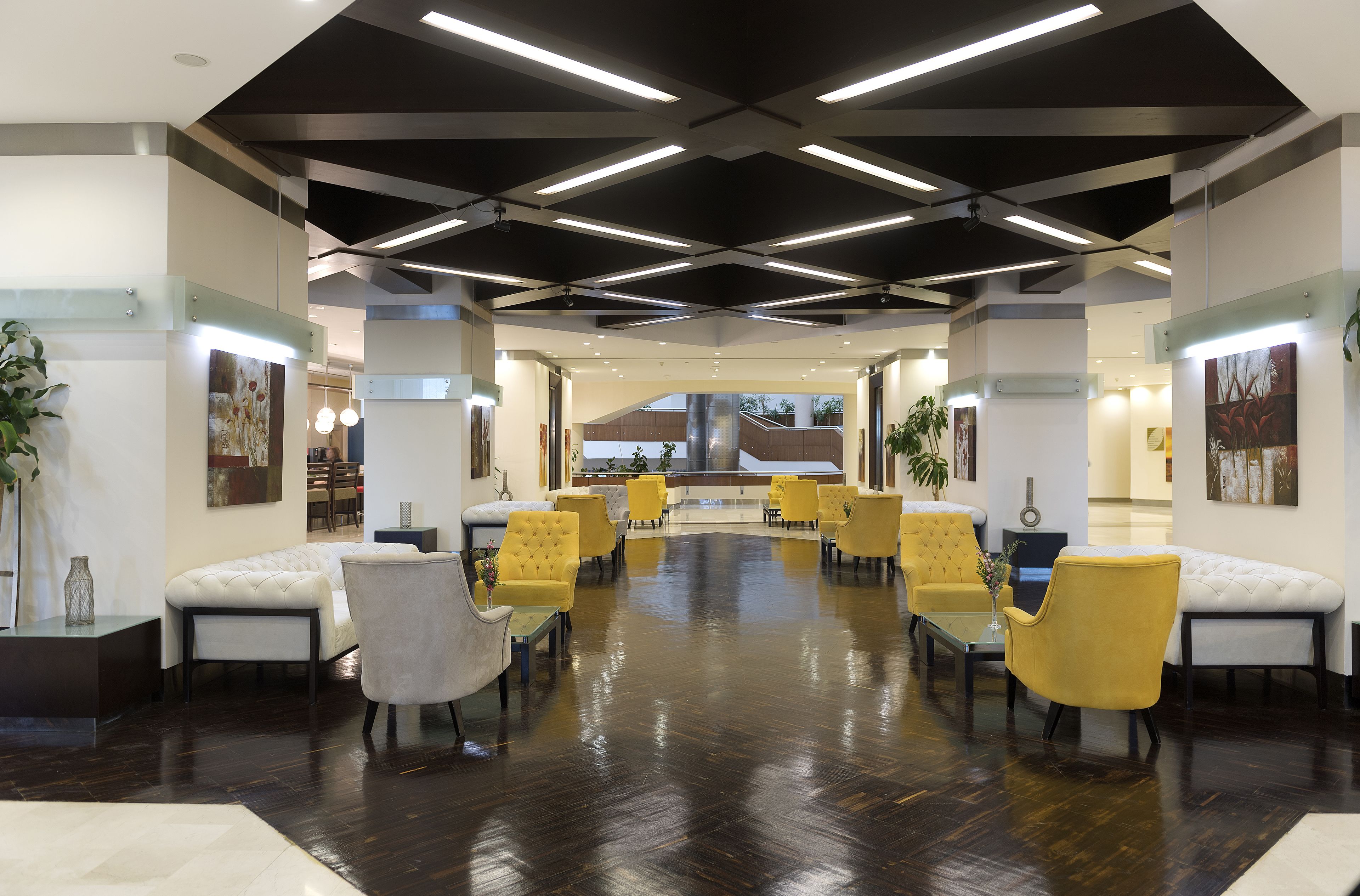 A spacious lobby with modern furniture, a high ceiling with exposed beams, and artwork on the walls.