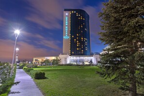 Un moderno edificio de hotel con un cartel llamativo, un césped bien cuidado y una farola.