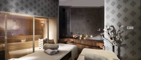 Un cuarto de spa con dos camas, paneles de madera, una sauna y un jarrón decorativo con flores.