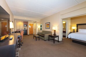 A hotel room with a bed, a desk, a chair, a sofa, and a small table. - Holiday Inn Express & Suites Jacksonville Airport by IHG (Jacksonville)