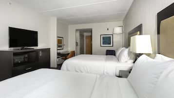 A hotel room with two beds, a TV, a desk, and a lamp.