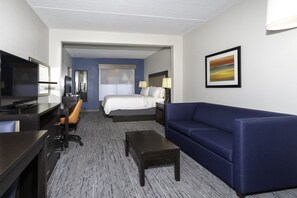 Une chambre d’hôtel équipée d’un lit, d’un bureau, d’une chaise, d’un canapé et d’une télévision.