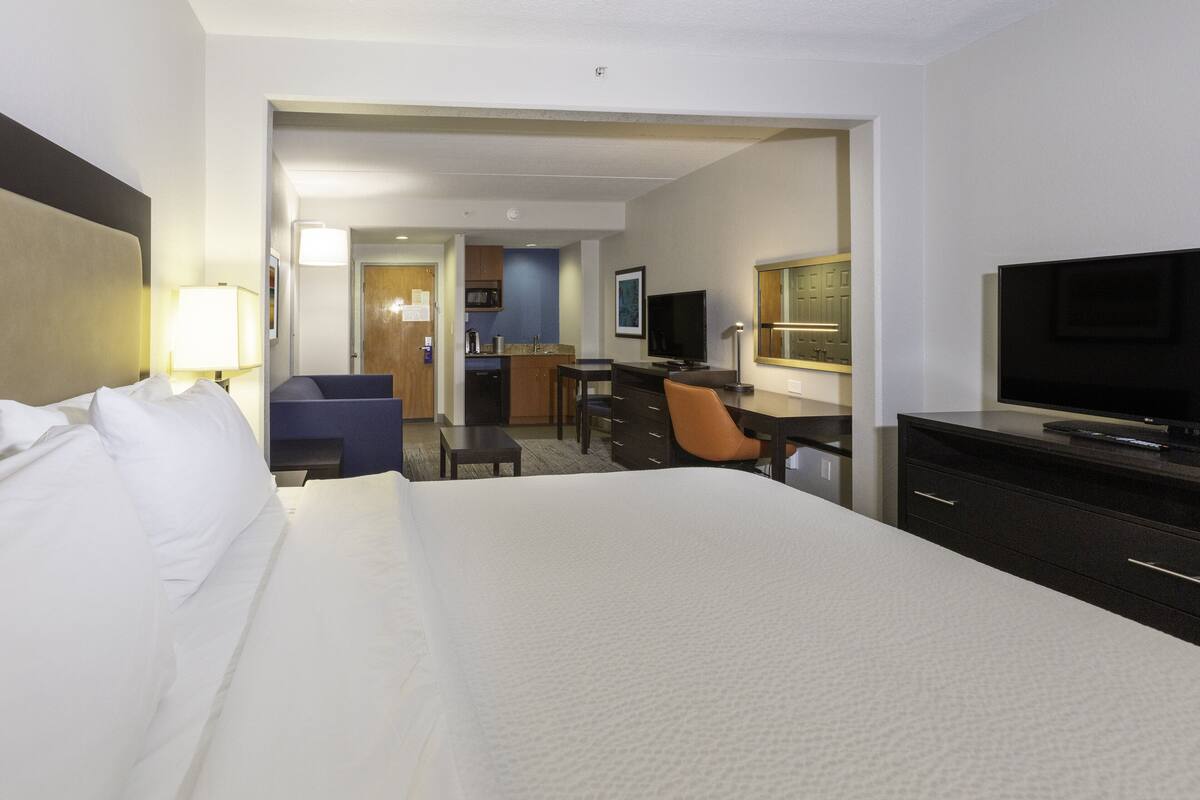 Une chambre d’hôtel dotée d’un grand lit, d’un bureau, d’une télévision et d’un coin cuisine.