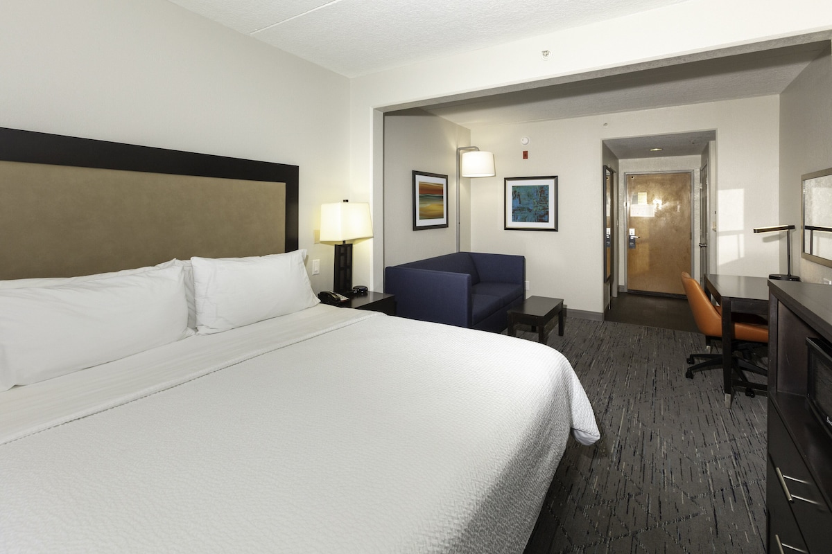 Una habitación de hotel con una cama grande, un escritorio, una silla y un televisor.