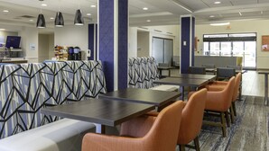 Eine moderne Hotelhalle mit Sitzbereichen, einer Kaffeestation und Blick nach außen.