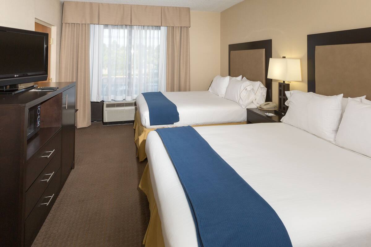 Une chambre d’hôtel avec deux lits, une télévision, un bureau avec une lampe et un téléphone.