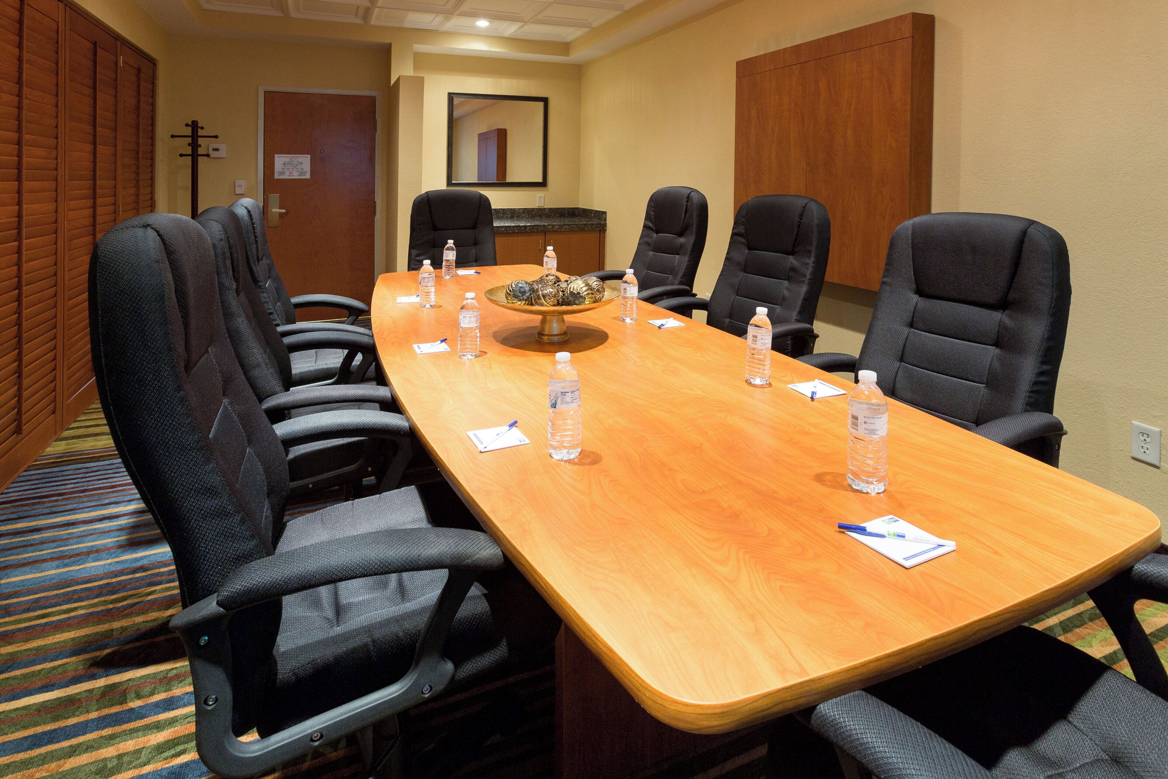 A conference room with a long table, six chairs, and water bottles.