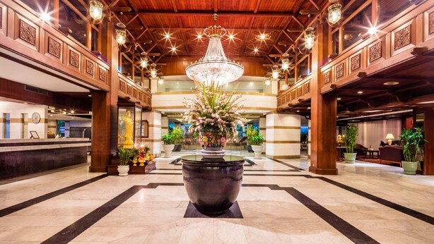 A spacious lobby with a large central fountain, wooden paneling, and a chandelier. - Bangkok Palace Hotel (Bangkok)
