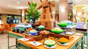 A buffet setup with various food items in bowls and a decorative windmill centerpiece. - Bangkok Palace Hotel (Bangkok)
