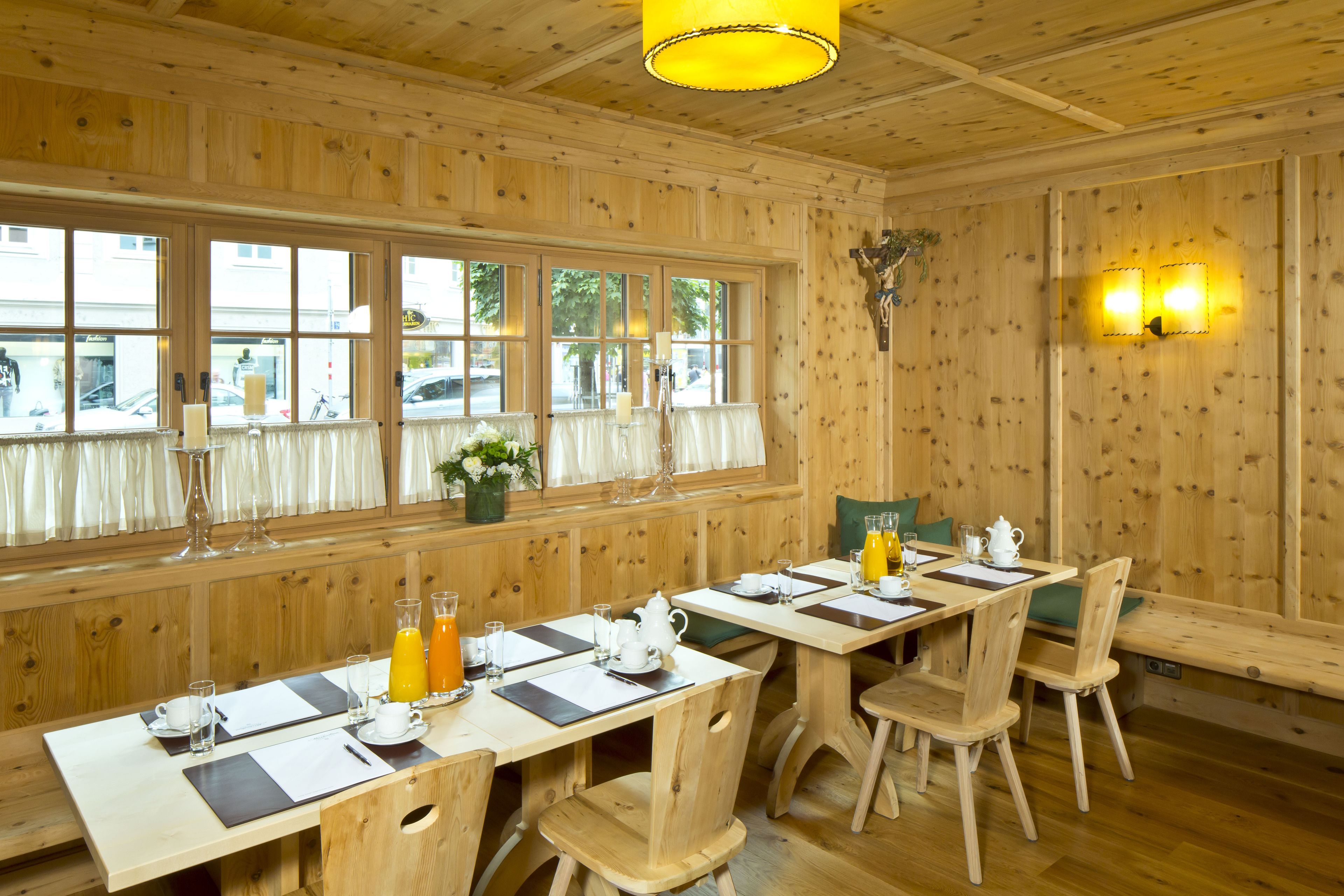 Une pièce aux murs lambrés, avec une longue table à manger dressée pour le petit-déjeuner, agrémentée d’un vase de fleurs, d’une carafe de jus d’orange et d’une cafetière.