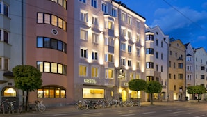 Un hôtel à plusieurs étages, une rangée de vélos devant l’entrée et un ciel dégagé.