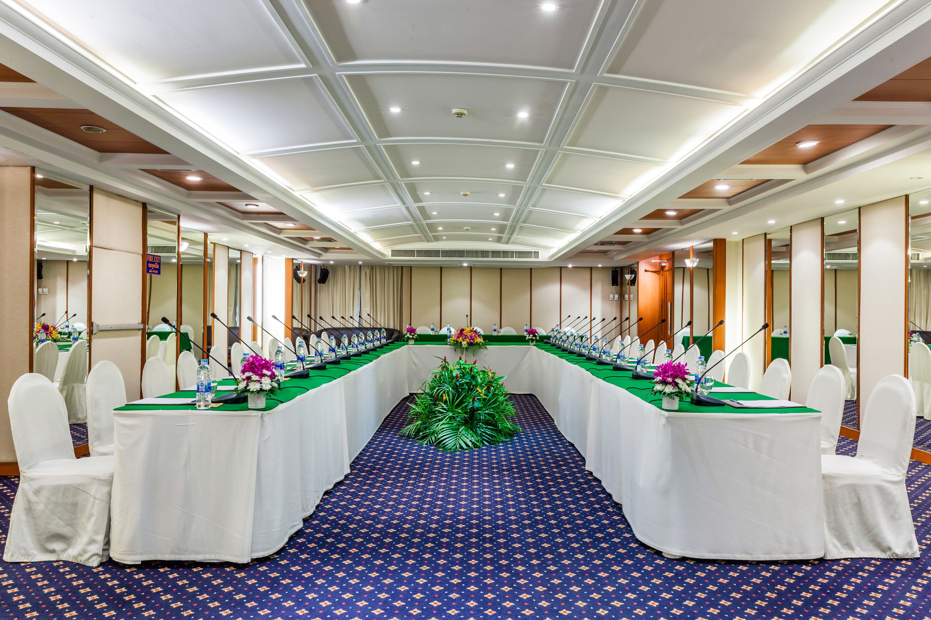 A conference room with a long table, white chairs, and a blue patterned carpet.