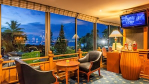 Habitación de hotel con un ventanal grande que ofrece vista a la ciudad, televisión y una pequeña mesa con sillas.