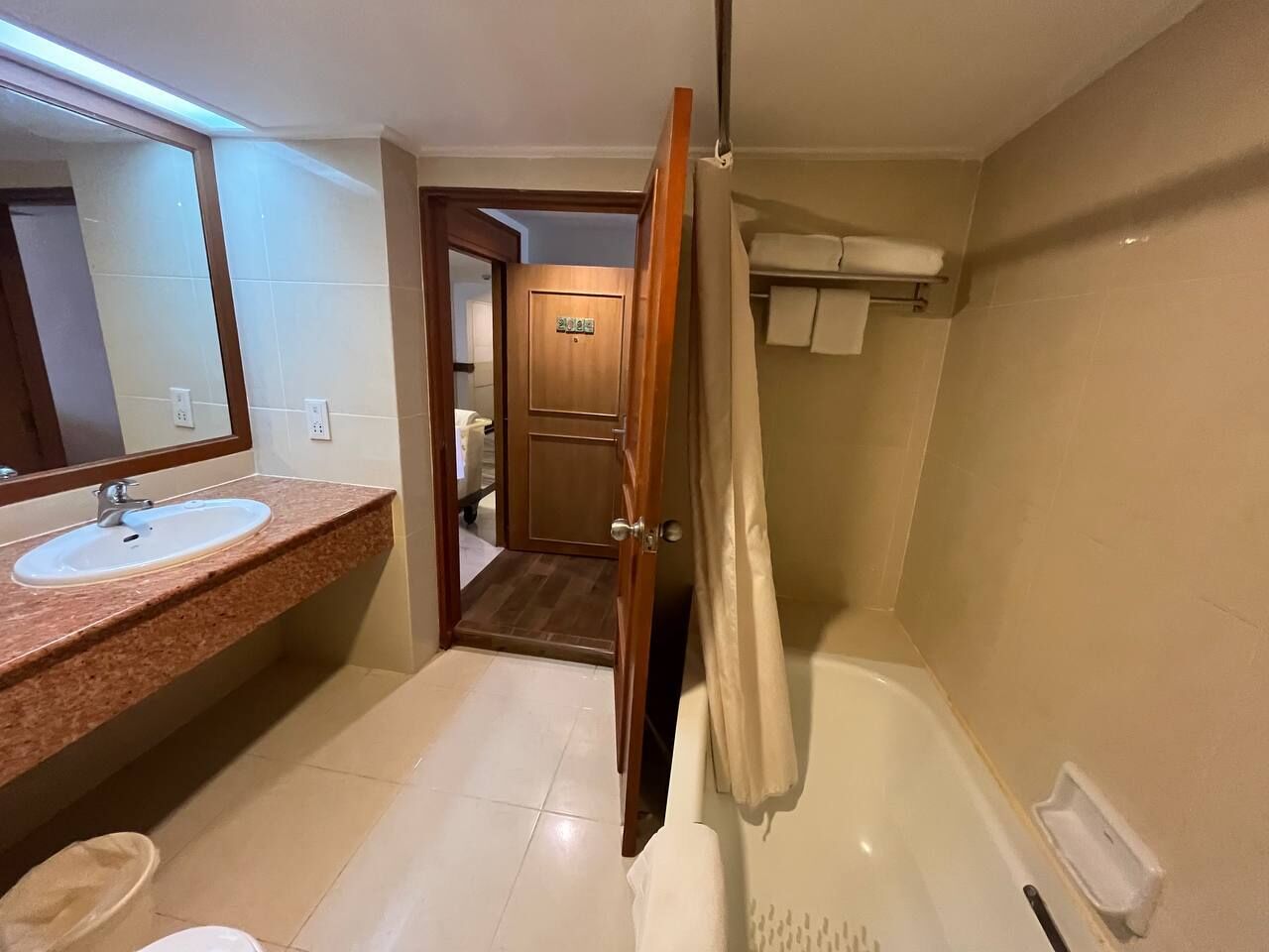 A bathroom with a sink, mirror, and bathtub.