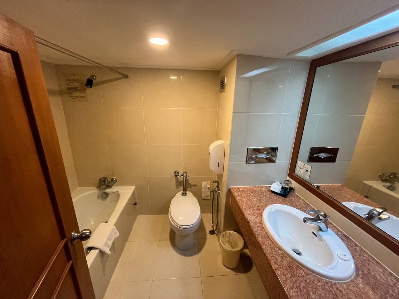 A bathroom with a bathtub, toilet, and sink, featuring a mirror and tiled walls.