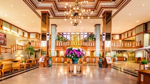 Un vestíbulo amplio con un arreglo floral central, muebles de madera y una araña.