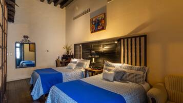 Habitación de hotel con dos camas, un espejo grande, un cuadro en la pared y techo de madera.