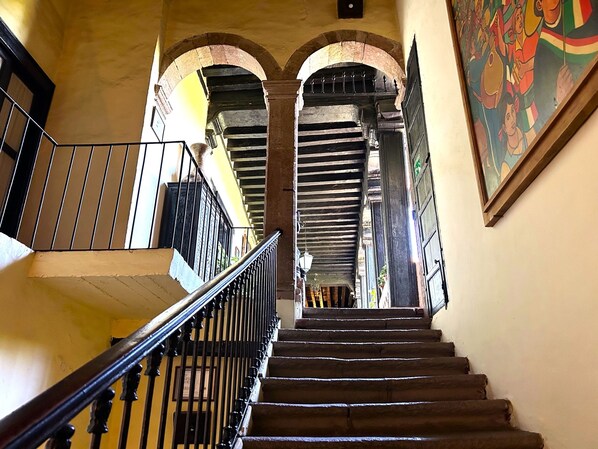 A staircase with a black handrail and a railing, leading to an arched doorway.
