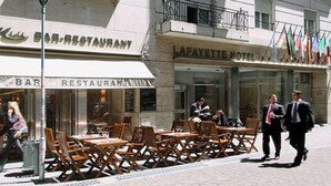 A bar and restaurant with outdoor seating and a hotel in the background. - Lafayette Hotel (Buenos Aires)