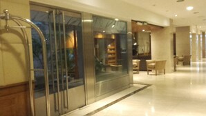 A modern hotel lobby with a glass partition, a reception desk, and a seating area with chairs. - Lafayette Hotel (Buenos Aires)