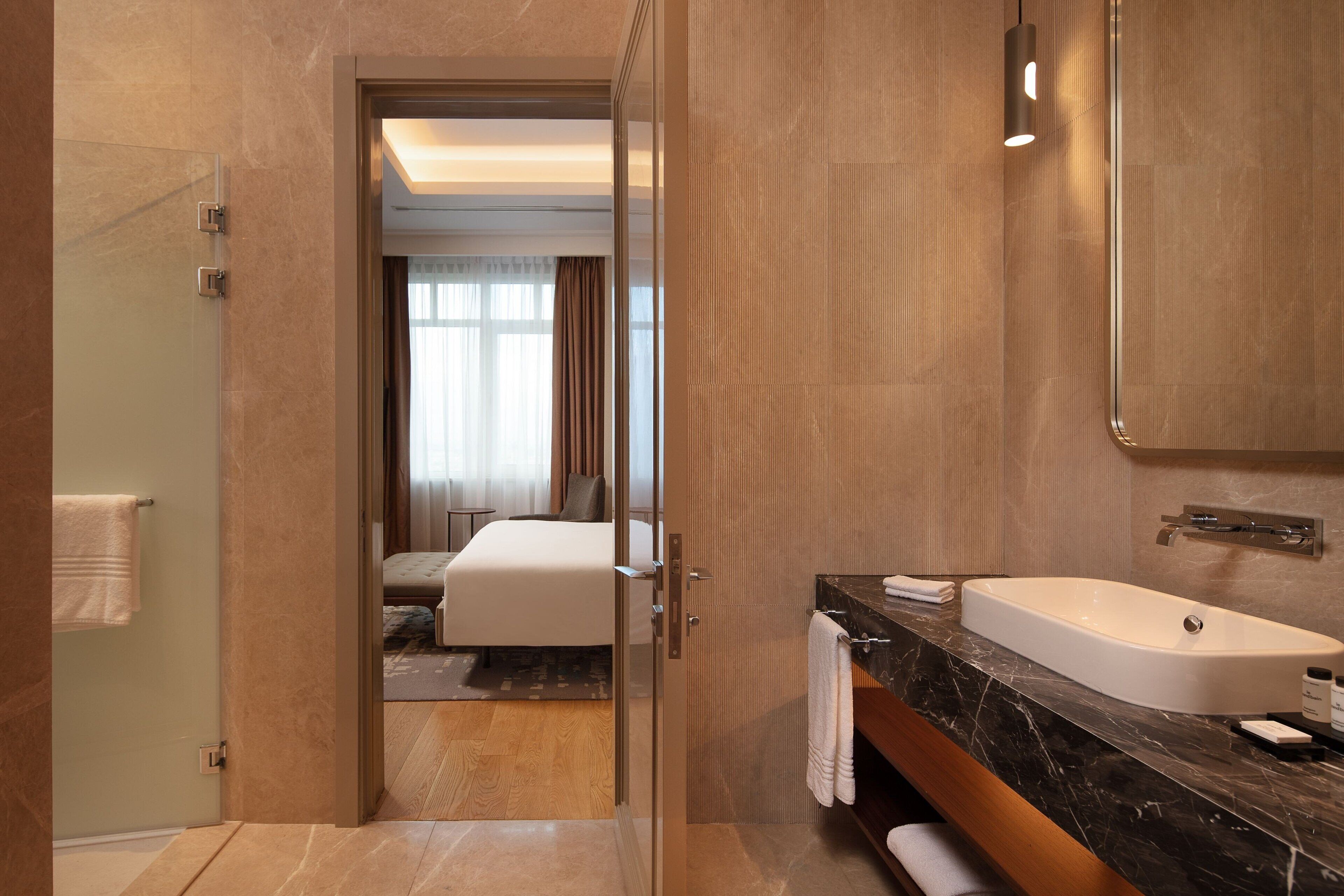 Une salle de bain moderne avec une grande baignoire, une douche à l’italienne en verre et un meuble-lavabo en bois.