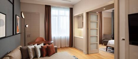 A modern hotel room with a sofa, a desk, a TV, and a bed.