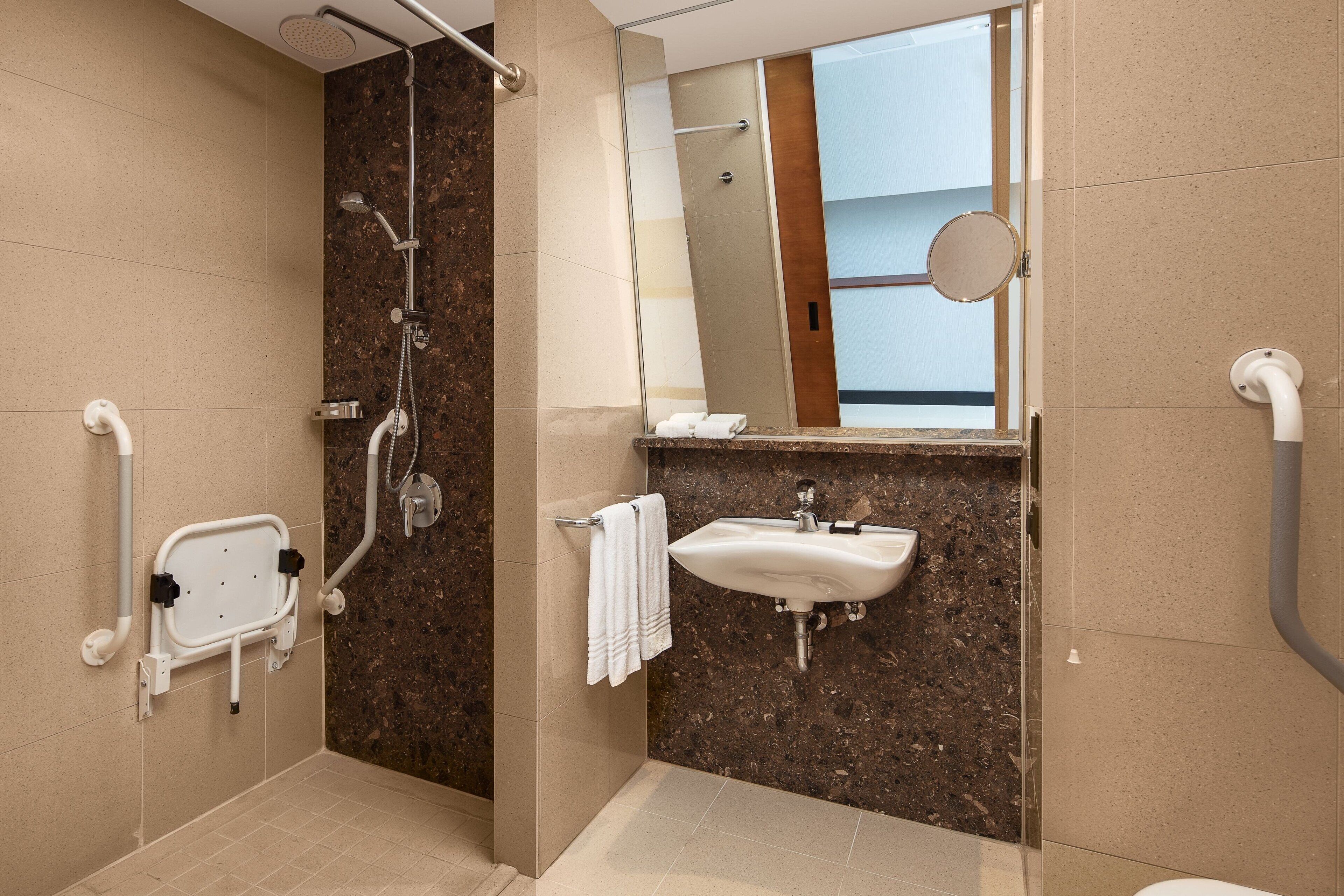 Een moderne badkamer met een douche, wastafel en een handgreep.