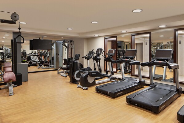 Un gimnasio con cintas de correr, elípticas y equipo de pesas.