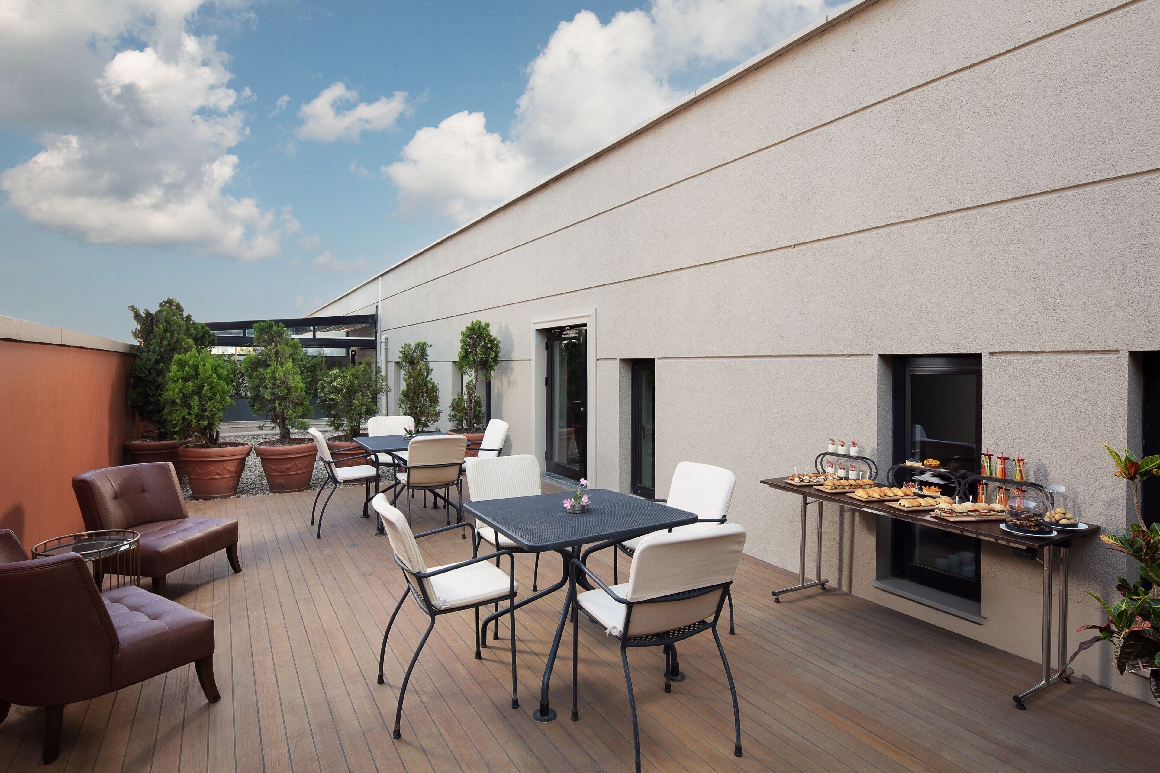 An outdoor patio with a dining table, chairs, and a grill area.