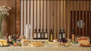A buffet table with various food items, including cheese, bread, and salads, and several bottles of wine.