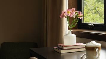 A table with a vase of flowers, a book, and a cup of coffee.