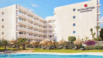 Una piscina al aire libre, sillones reclinables de piscina