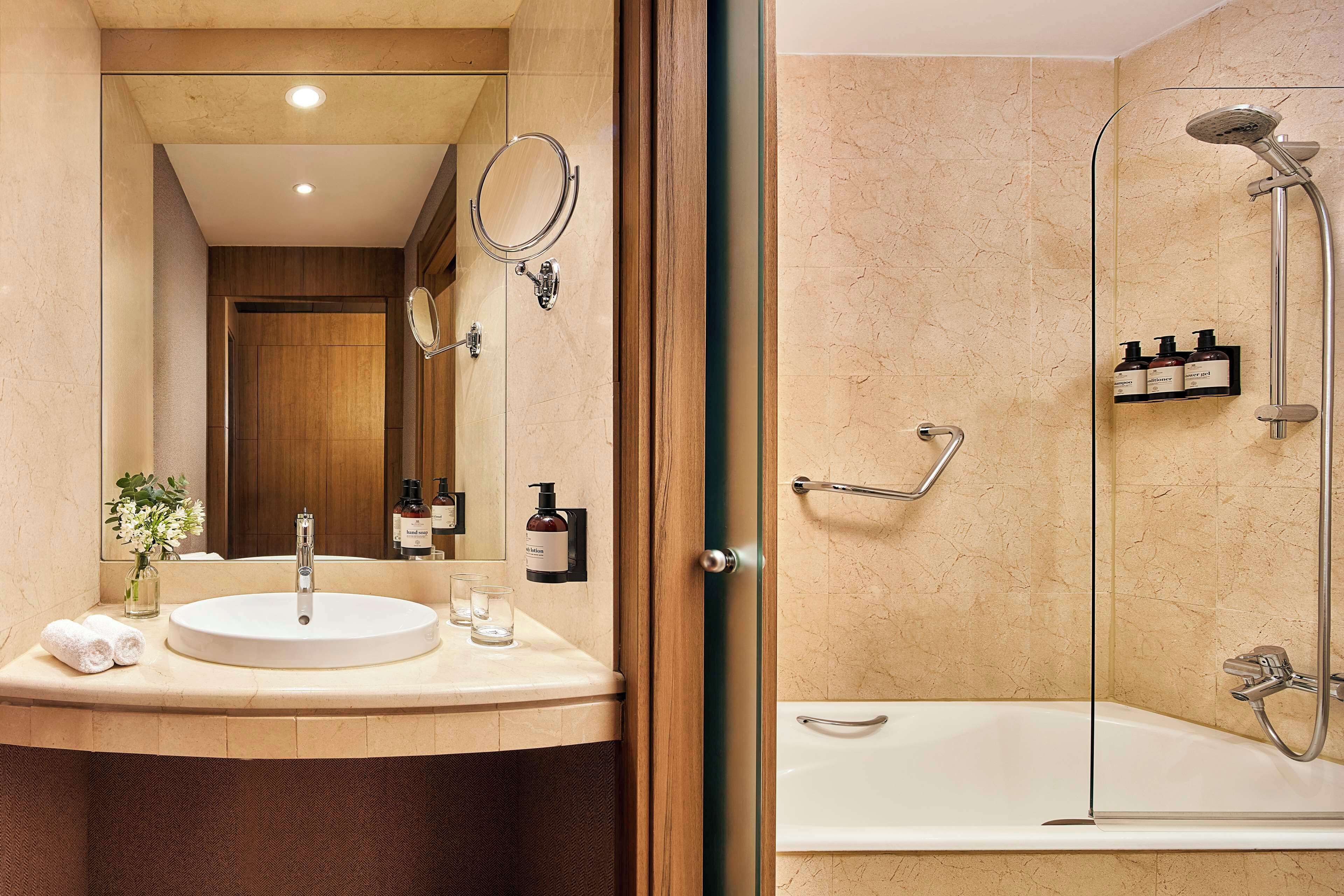 Een moderne badkamer met een rond wastafel, een douche met glazen wanden en een spiegel boven de wastafel.