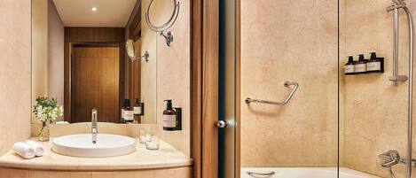 A modern bathroom with a round sink, a glass-enclosed shower, and a mirror above the sink.